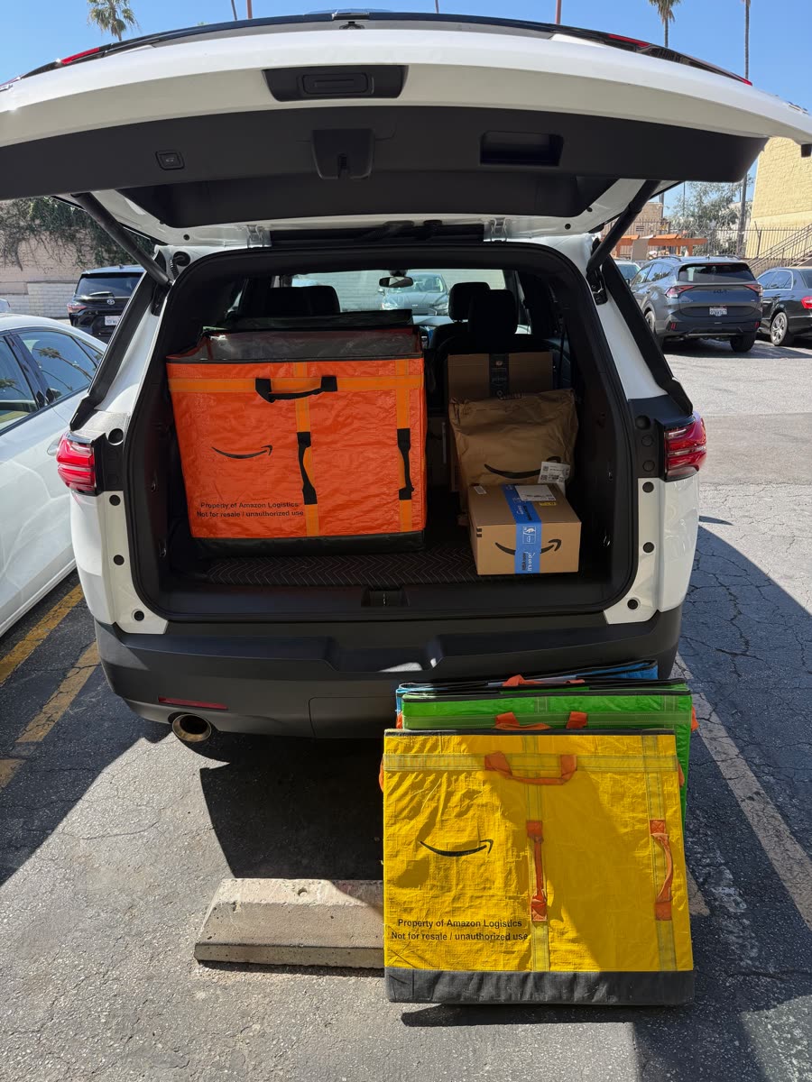 Amazon packages and delivery containers beside a loaded vehicle